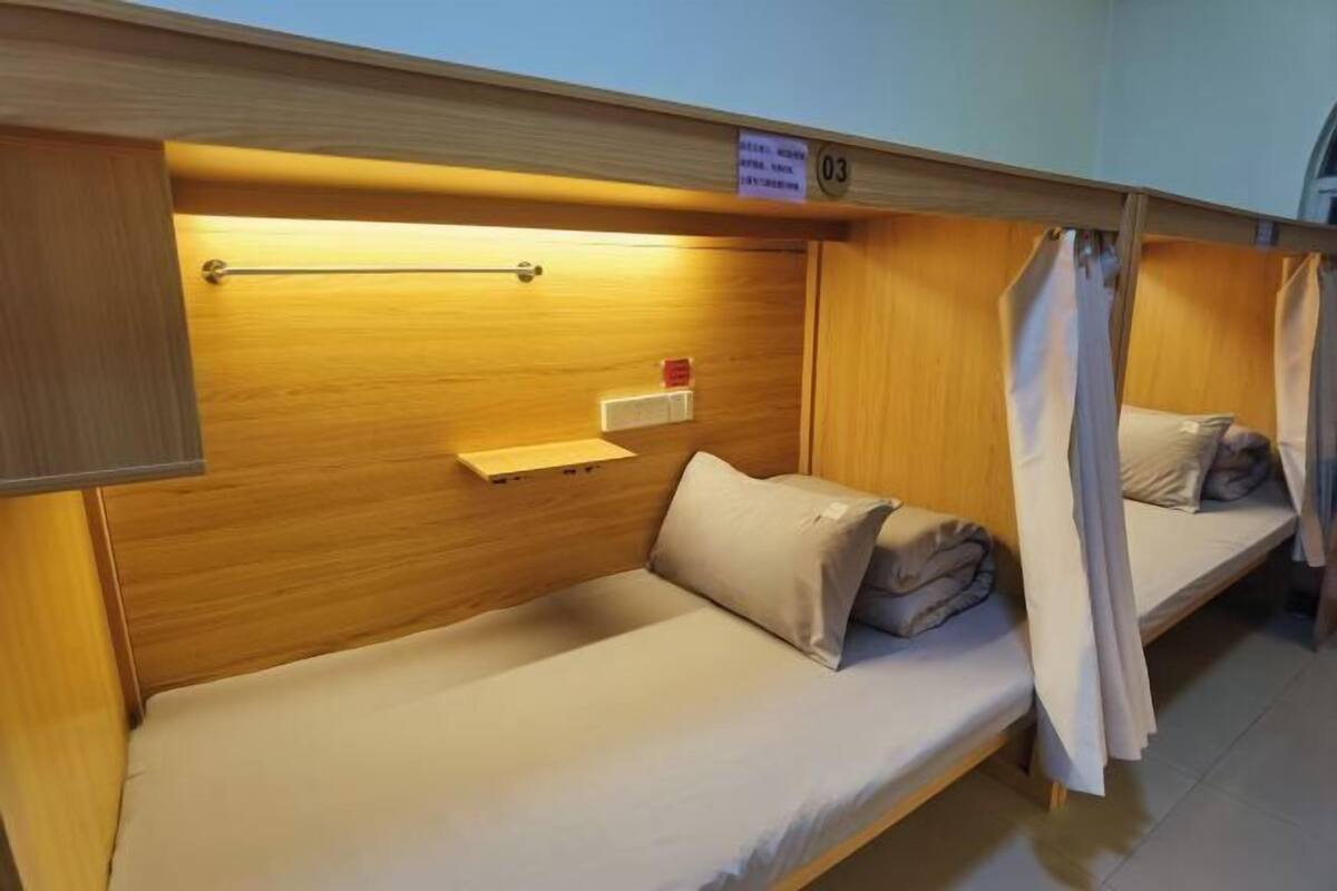 A bunk bed room with a wooden headboard, a small shelf, and a red object on the wall.