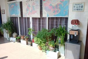 A reception area with a coffee machine, potted plants, and maps on the wall. - Beret B&B (Tengchong)