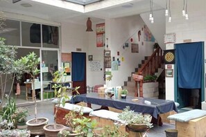 A room with a table, chairs, potted plants, and a staircase. - Beret B&B (Tengchong)