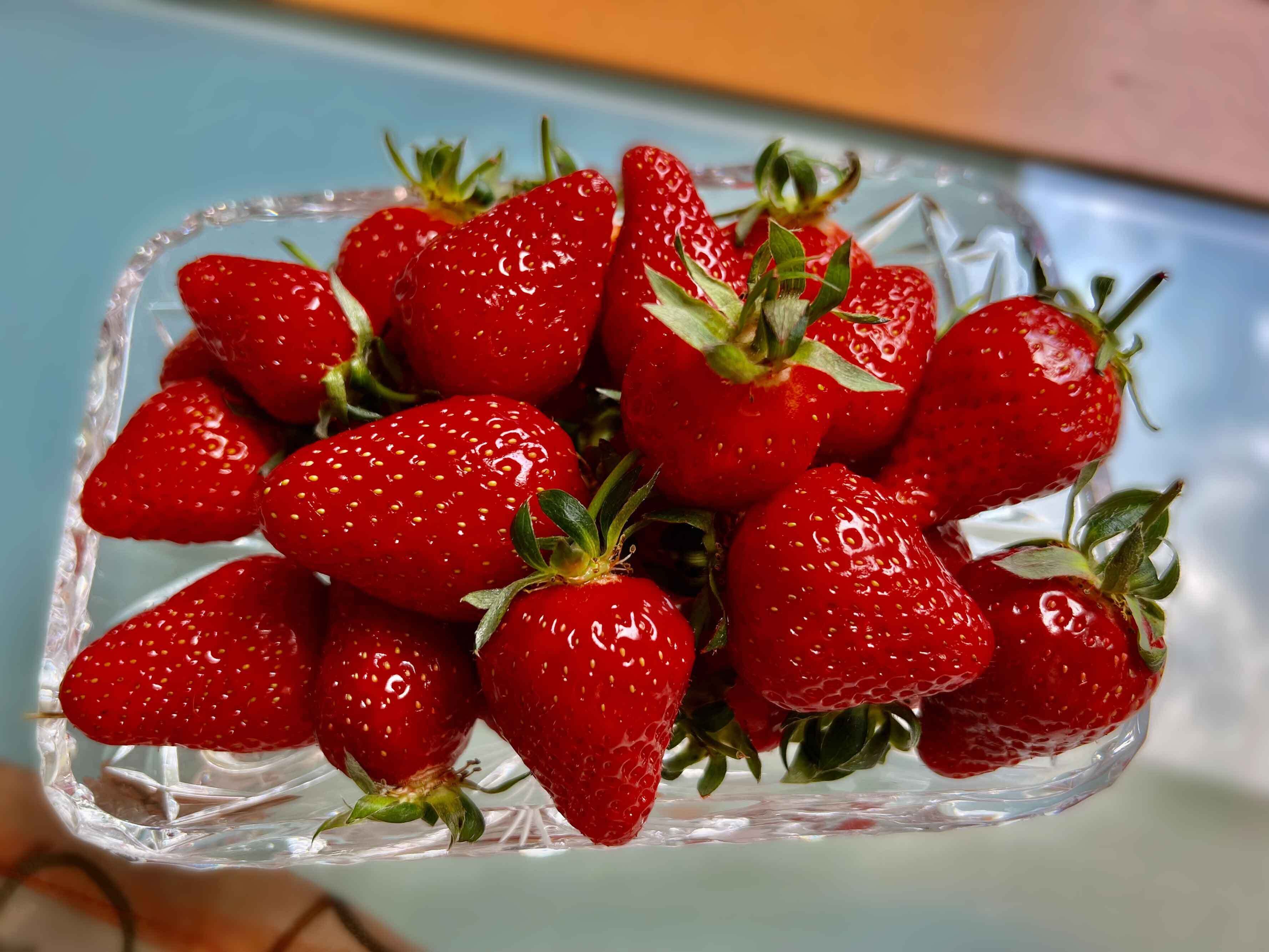 A clear glass bowl filled with fresh strawberries.