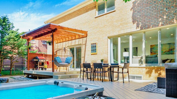 Un jardin avec un jacuzzi, un coin salon extérieur et une maison en briques.