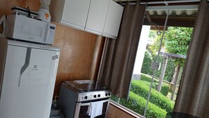 A compact kitchen with a refrigerator, stove, and cabinets. - A Nossa Casinha (Campos do Jordão)