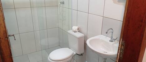 A small bathroom with a toilet, sink, and shower.