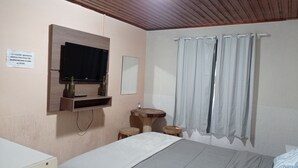 A bedroom with a bed, a TV mounted on the wall, a small round table, and a mirror. - A Nossa Casinha (Campos do Jordão)