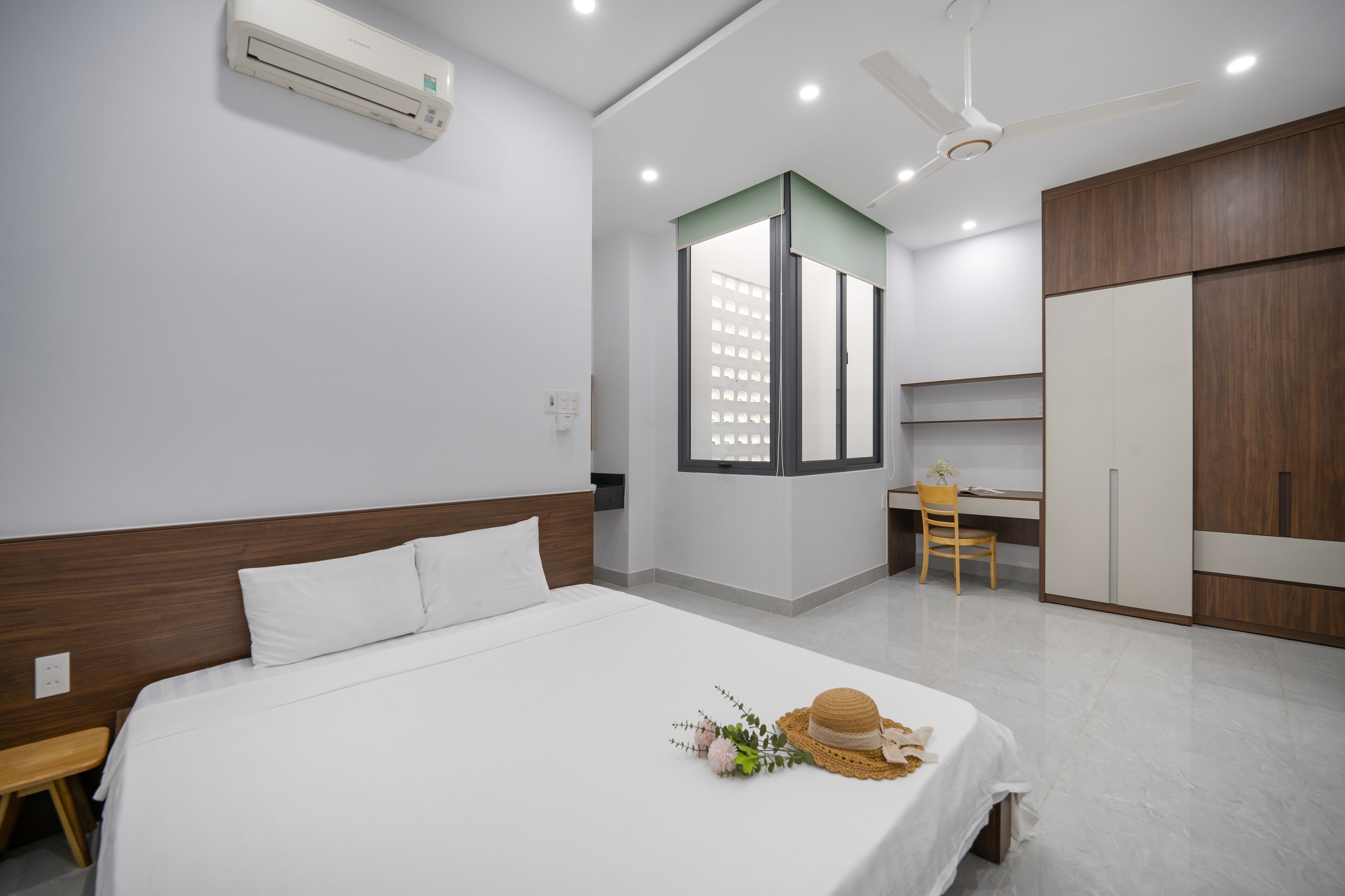 A modern hotel room with a large bed, a desk, and a wardrobe.