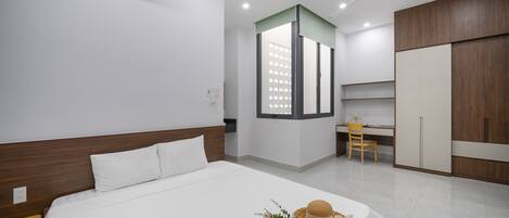 A modern hotel room with a large bed, a desk, and a wardrobe.