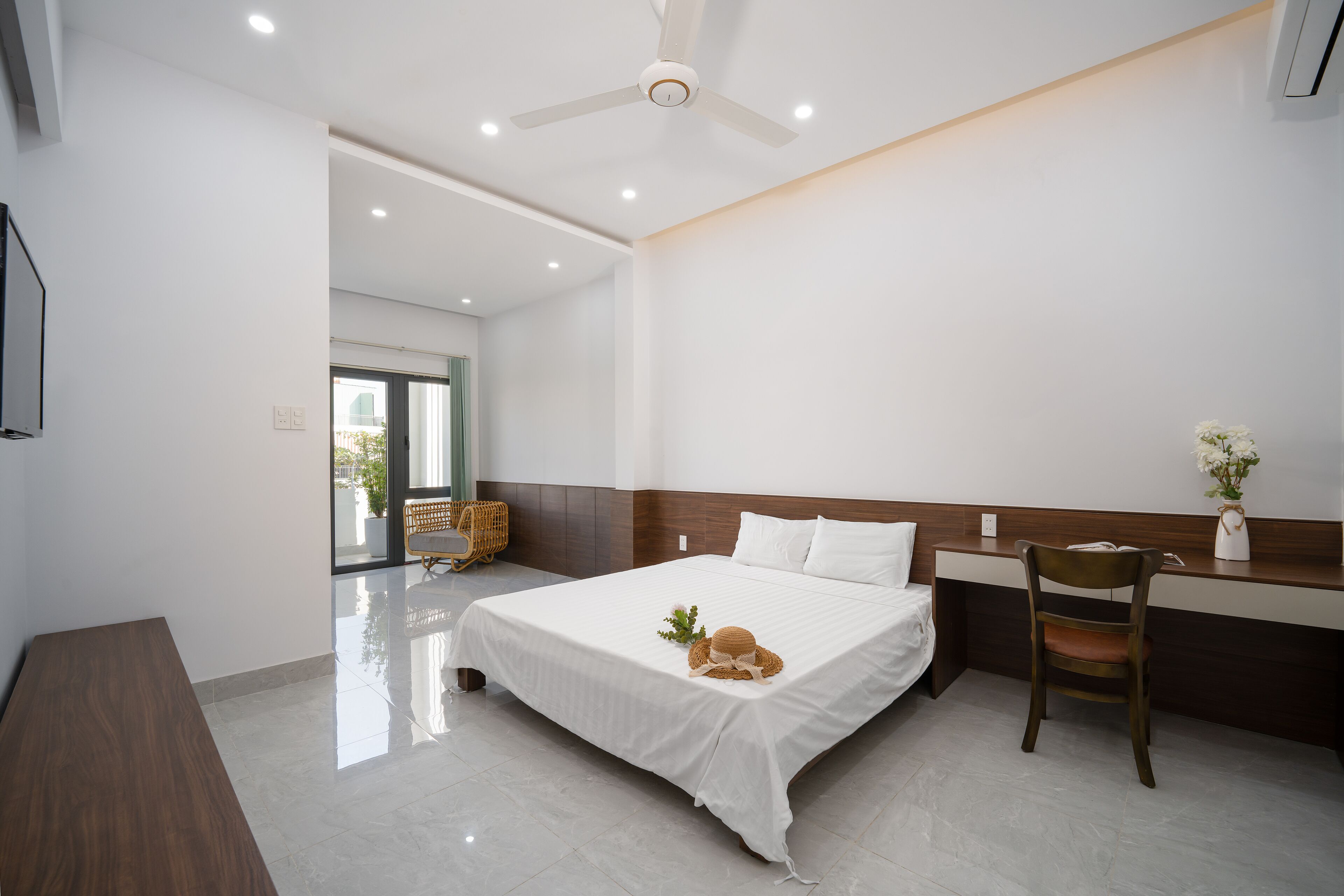 A modern hotel room with a large bed, a desk, and a chair.