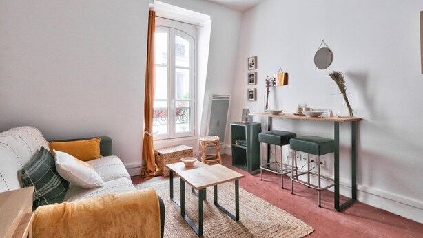 A living room with a sofa, coffee table, and a dining area with a small table and stools.