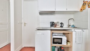 A compact kitchen with white cabinets, a built-in microwave, a coffee maker, and a sink.