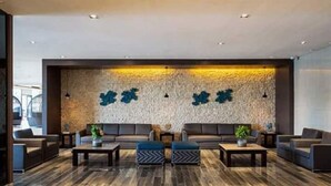 A modern lobby with a stone wall, seating area, and wooden flooring. - Serenity Cove MOA Cozy condo unit amenity view. (Pasay)