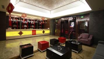 A lobby with a reception desk, seating area, and a decorative ceiling.
