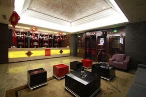 Un hall con mostrador de recepción, zona de estar y un techo decorativo.
