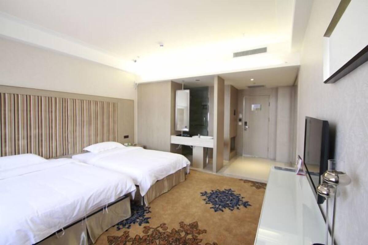 Una habitación de hotel con dos camas, un baño y un televisor.