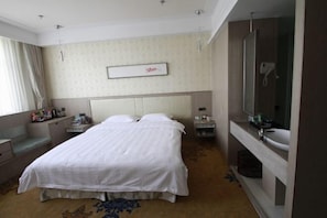 A hotel room with a bed, bedside tables, a mirror, and a bathroom with a sink and shower. - Linton Hotel (Huanan)