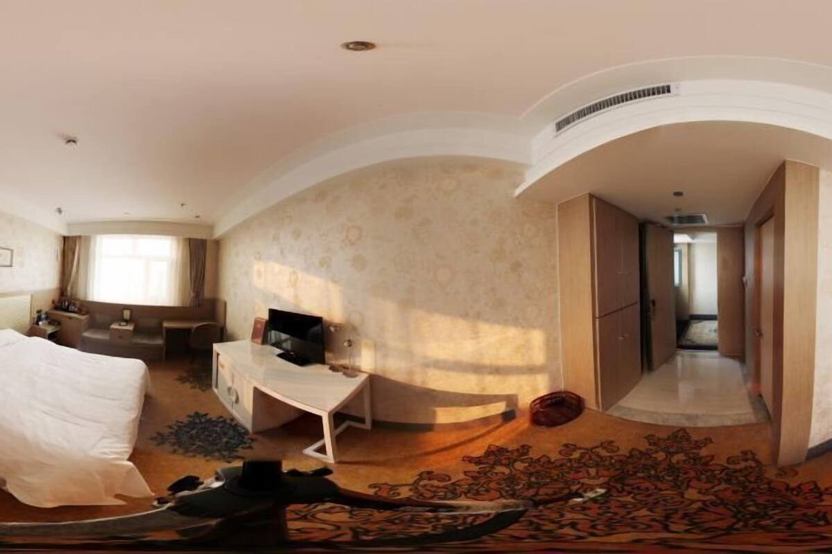 Una habitación de hotel amplia con una cama grande, un escritorio y un vestidor.