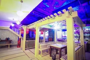 Un restaurante con un área de asientos con bancos de madera, una escalera y un techo con una lámpara azul.