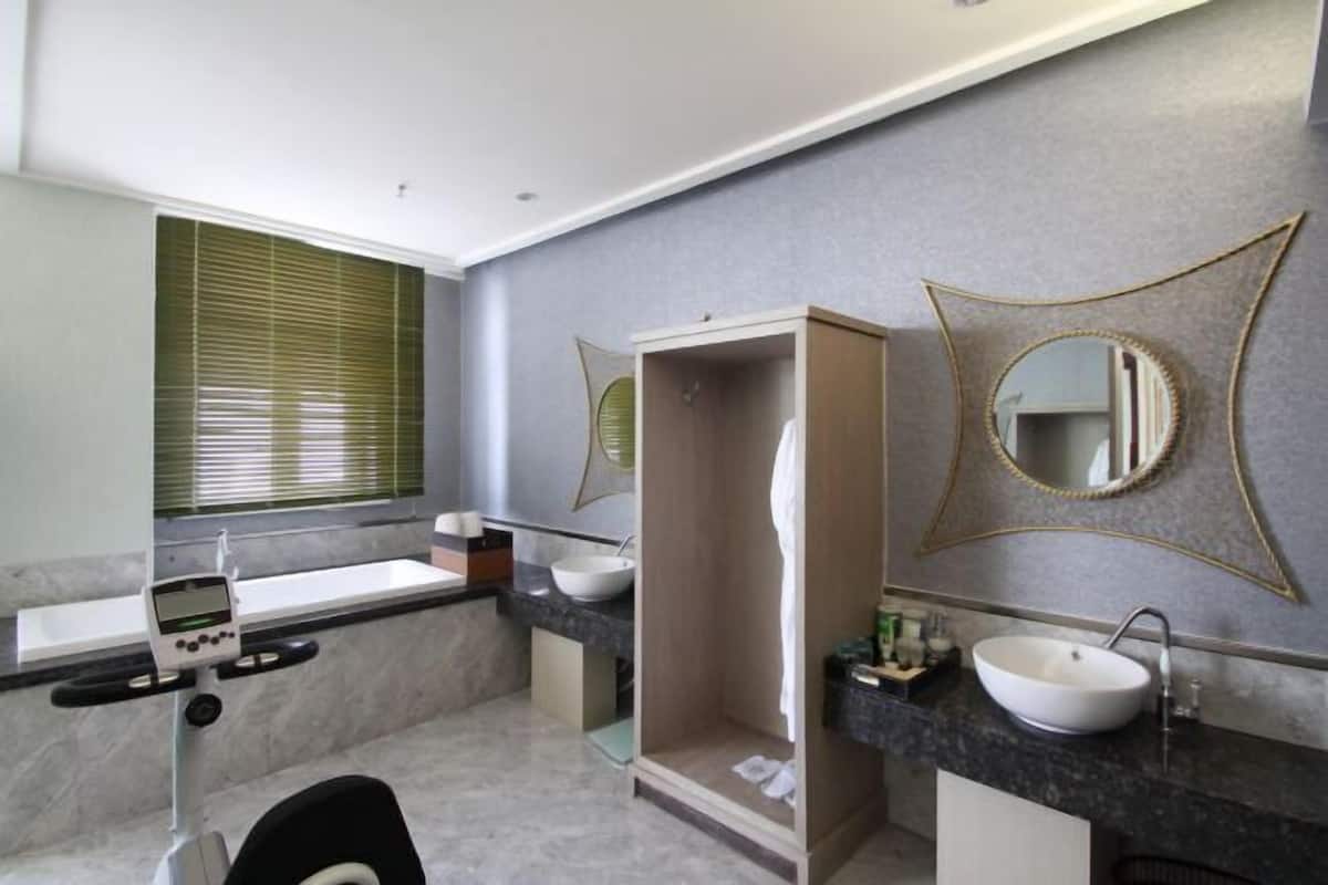 Un baño moderno con bañera, dos lavamanos, ducha y una cinta de correr.