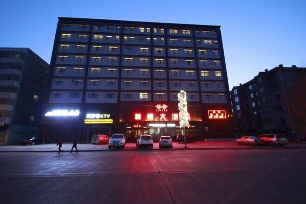 A multi-story building with illuminated signage, a pedestrian walkway, and parked cars. - Linton Hotel (Huanan)