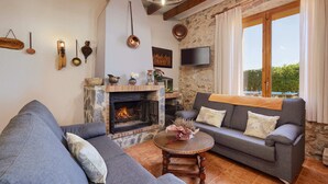 A cozy living room with a fireplace, a sofa, a coffee table, and a television. - Mas Ribas Turismo Rural (Ventallo)