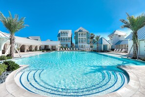 Une piscine entourée de bâtiments, avec un ciel bleu dégagé au-dessus.