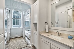 Une salle de bain moderne avec un grand miroir, un lavabo et une fenêtre.