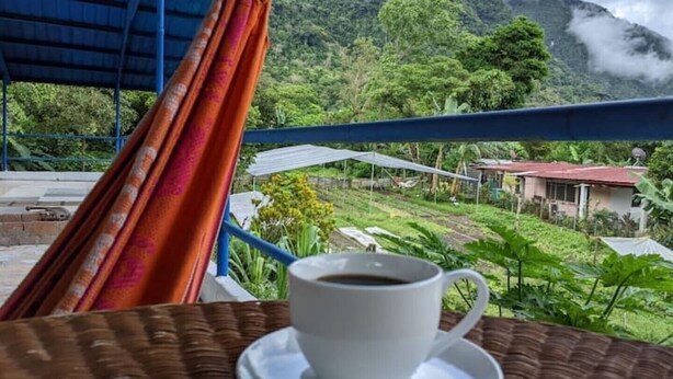 Una taza de café sobre una mesa con vistas a un paisaje montañoso.