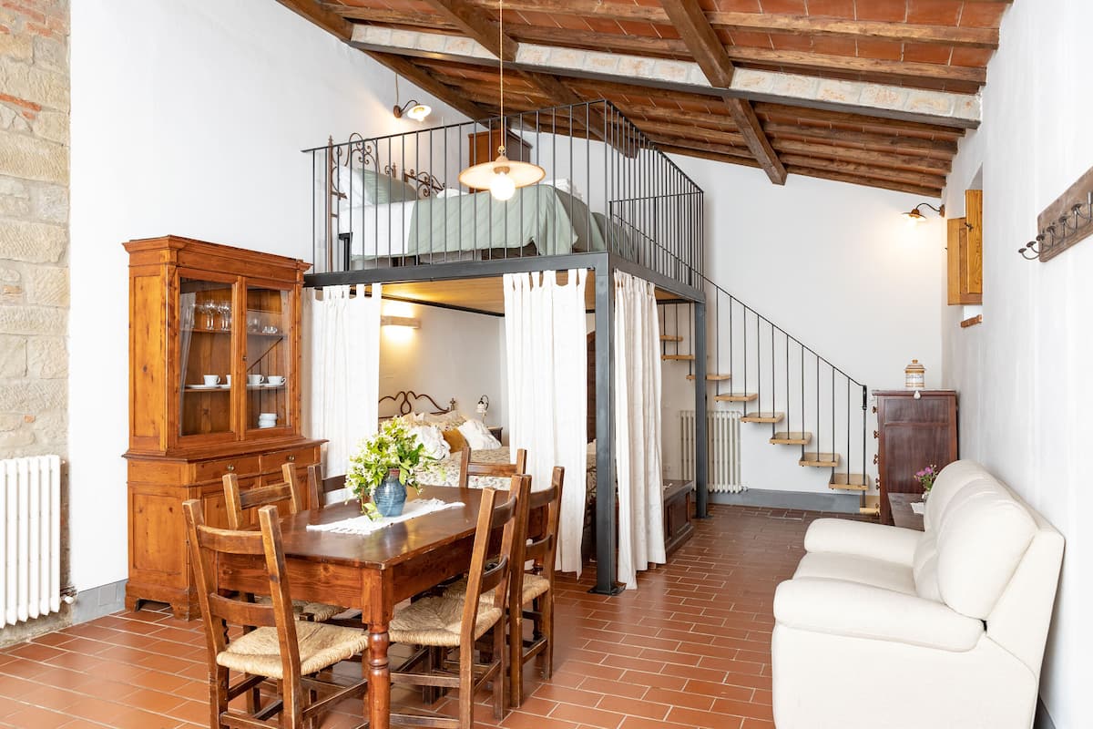 Ein Essbereich mit Holztisch und -stühlen, einem Schrank und einer Treppe, die zu einer oberen Ebene führt.