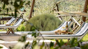 Terraza con sillones de descanso y una mesa con una botella y copas.