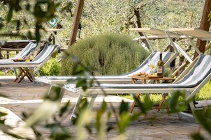 Terraza con sillones de descanso y una mesa con una botella y copas.