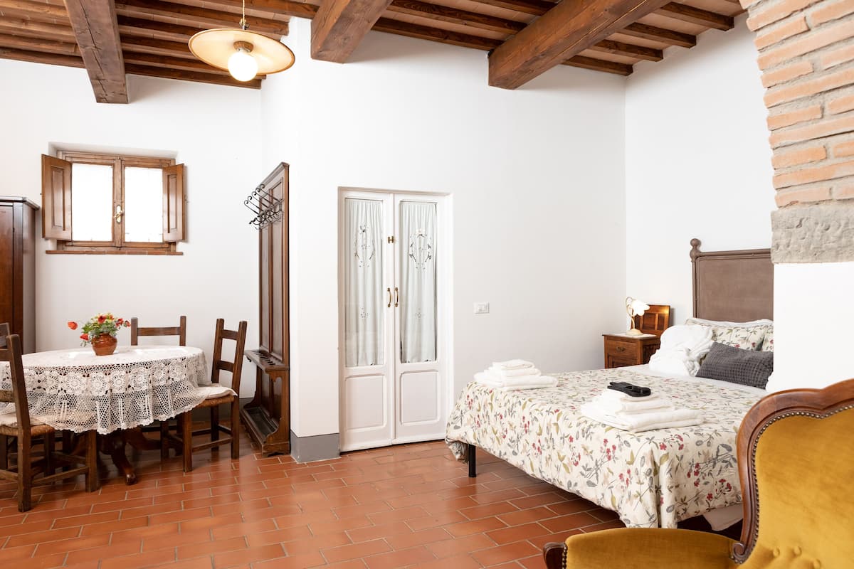 Ein Zimmer mit Bett, Tisch mit Stühlen, Kleiderschrank und Fenster.