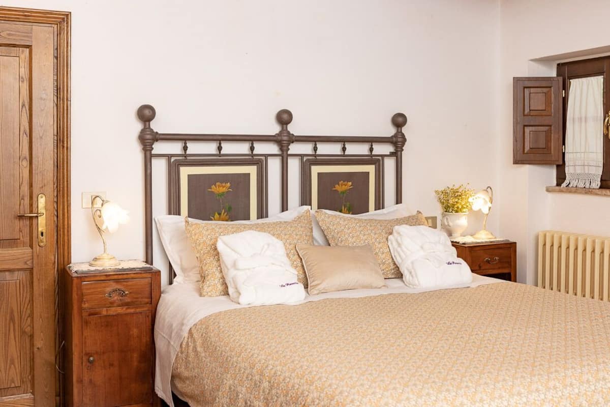 Ein ordentlich bezogenes Bett mit Blumenmuster, zwei Nachttische mit Lampen, ein Holzschrank und eine Heizung.