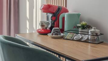 A kitchen counter with a coffee maker, a kettle, a sugar container, and a small potted plant.