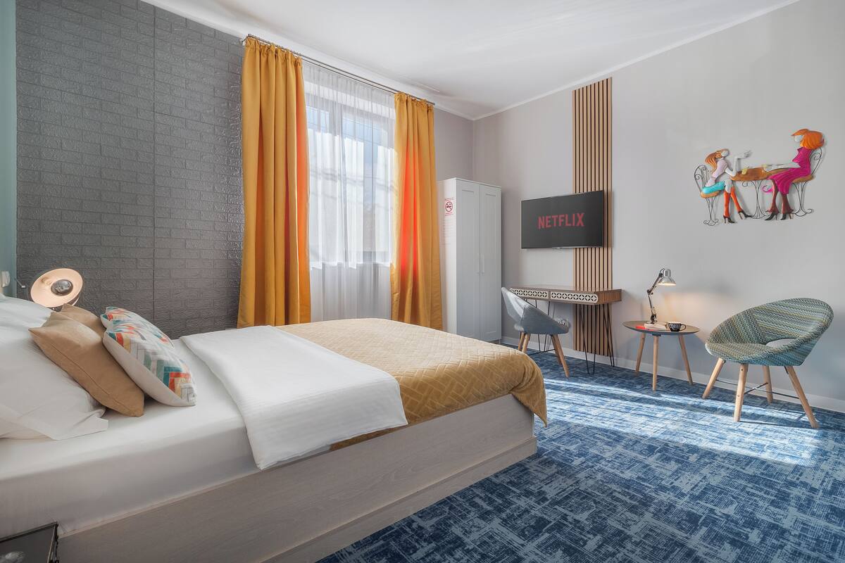 A hotel room with a bed, a TV, a desk, and a chair.