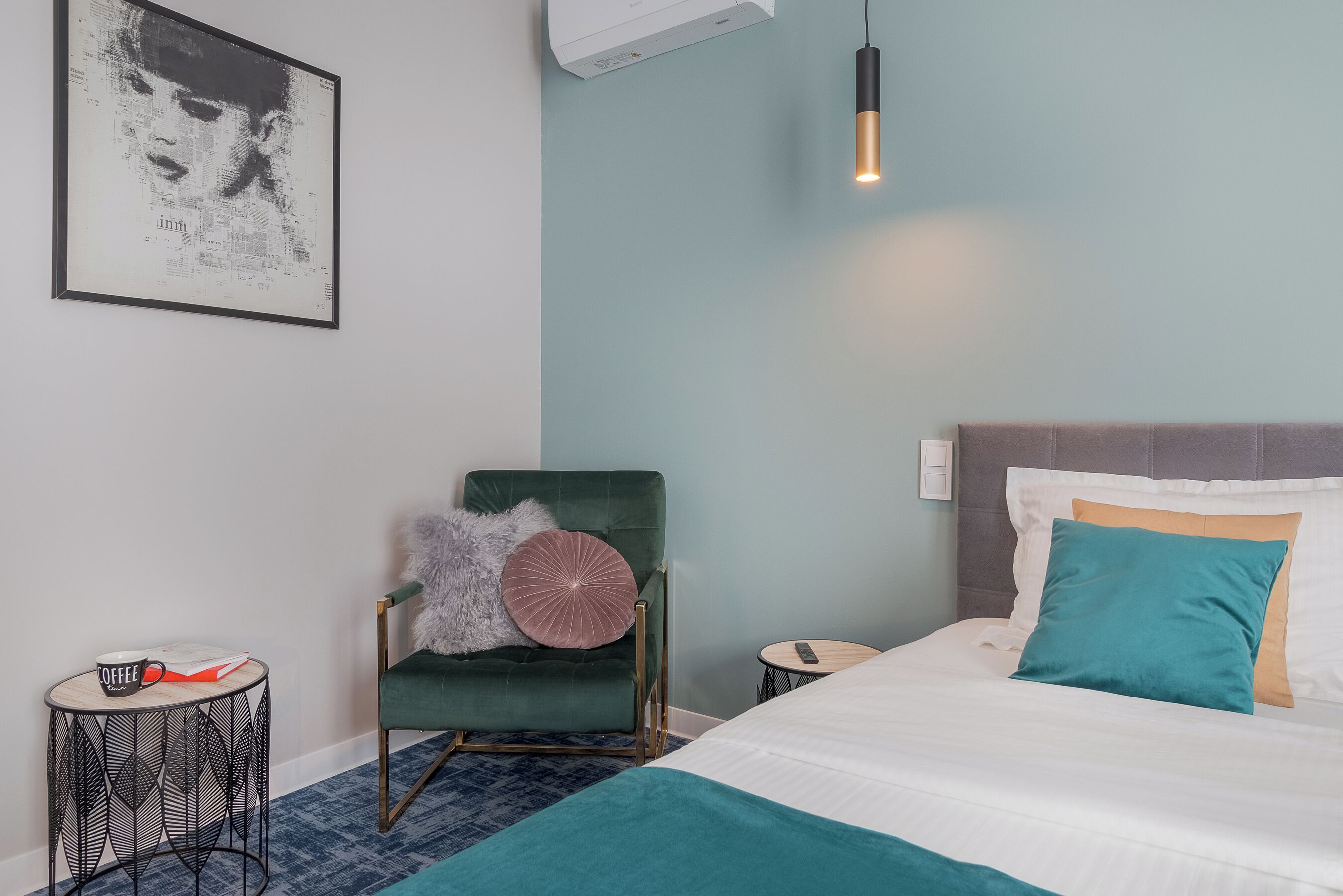 A neatly arranged bedroom with a bed, a chair, a small table, and a wall-mounted air conditioner.