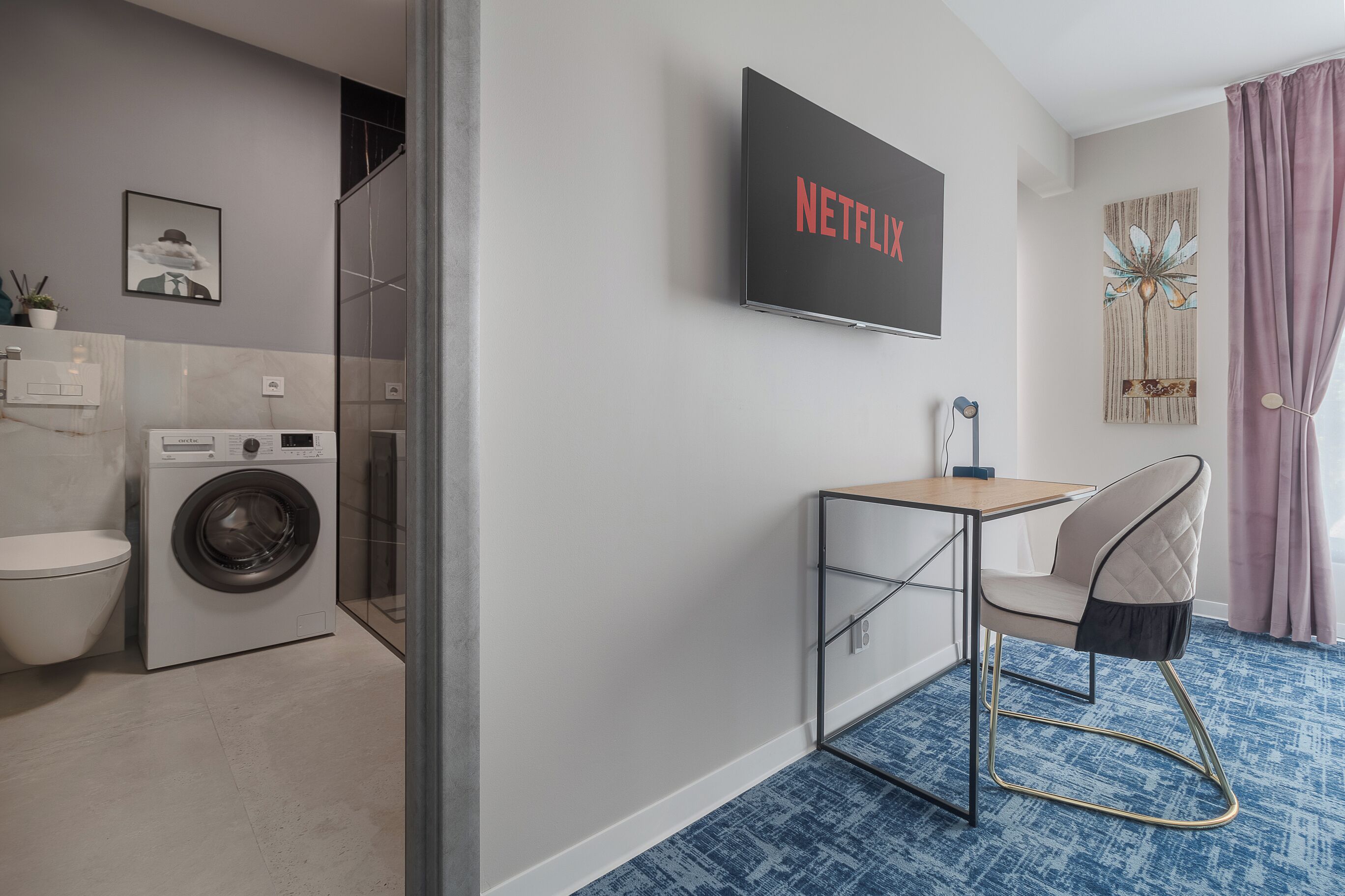 A modern bathroom with a washing machine, toilet, and a shower.