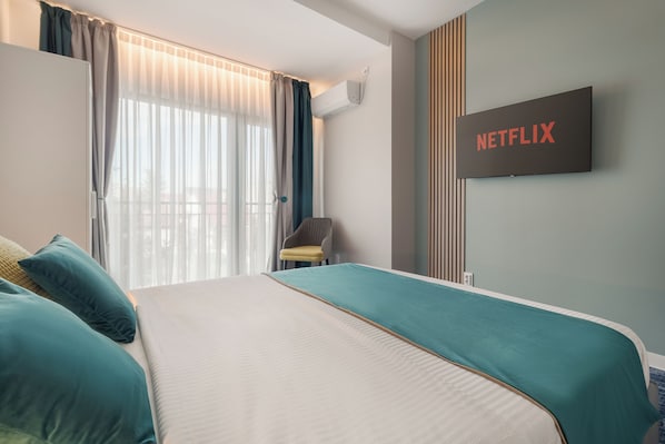A hotel room with a bed, a television mounted on the wall, and a window with curtains. - Aria Prestige Boutique (Oradea)