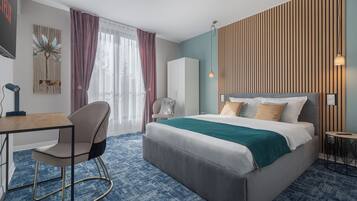 Een moderne hotelkamer met een bed, bureau, stoel en uitzicht op de omgeving.