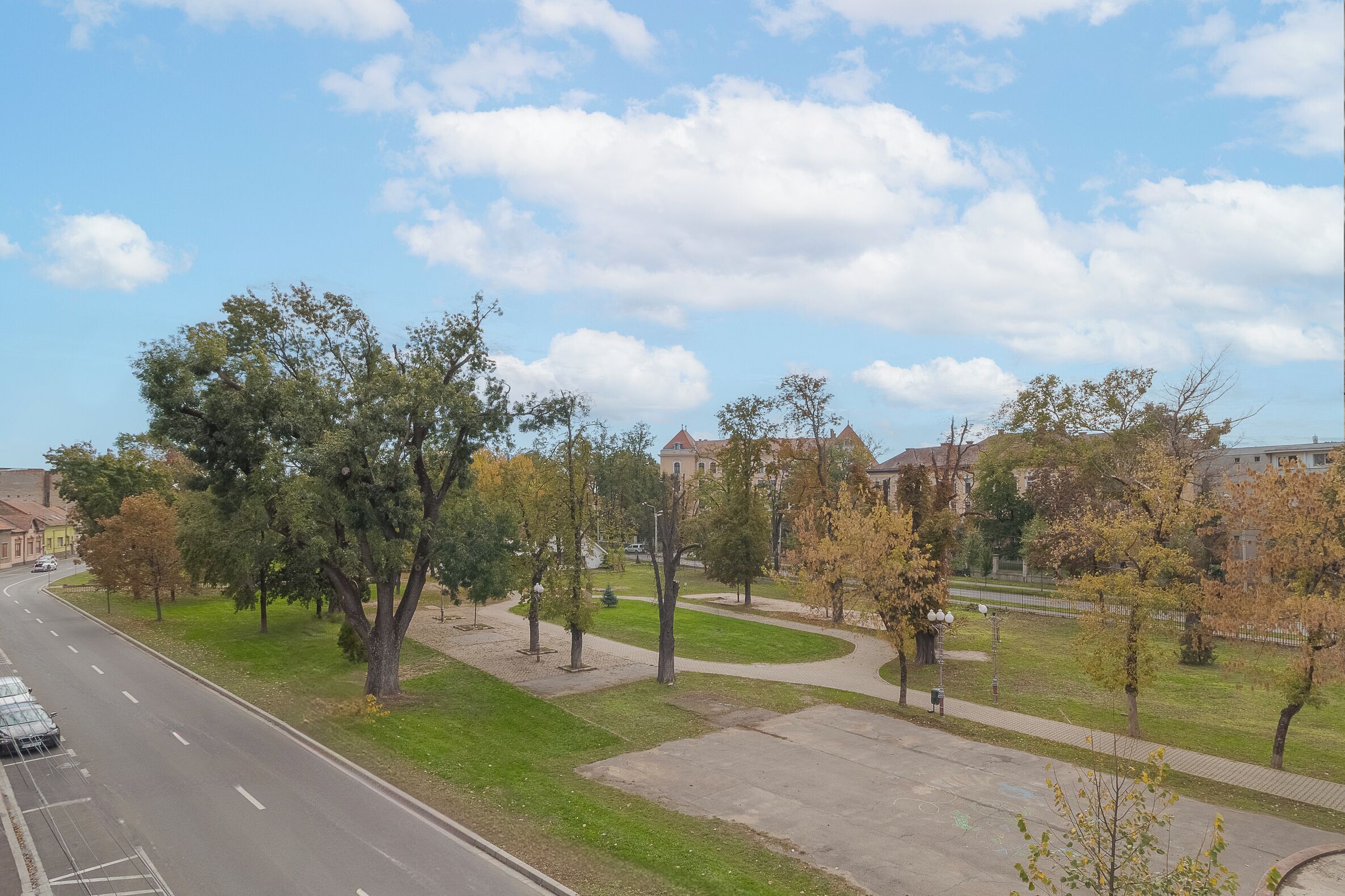 Une vue de rue avec une route sinueuse, des arbres et des bâtiments en arrière-plan.
