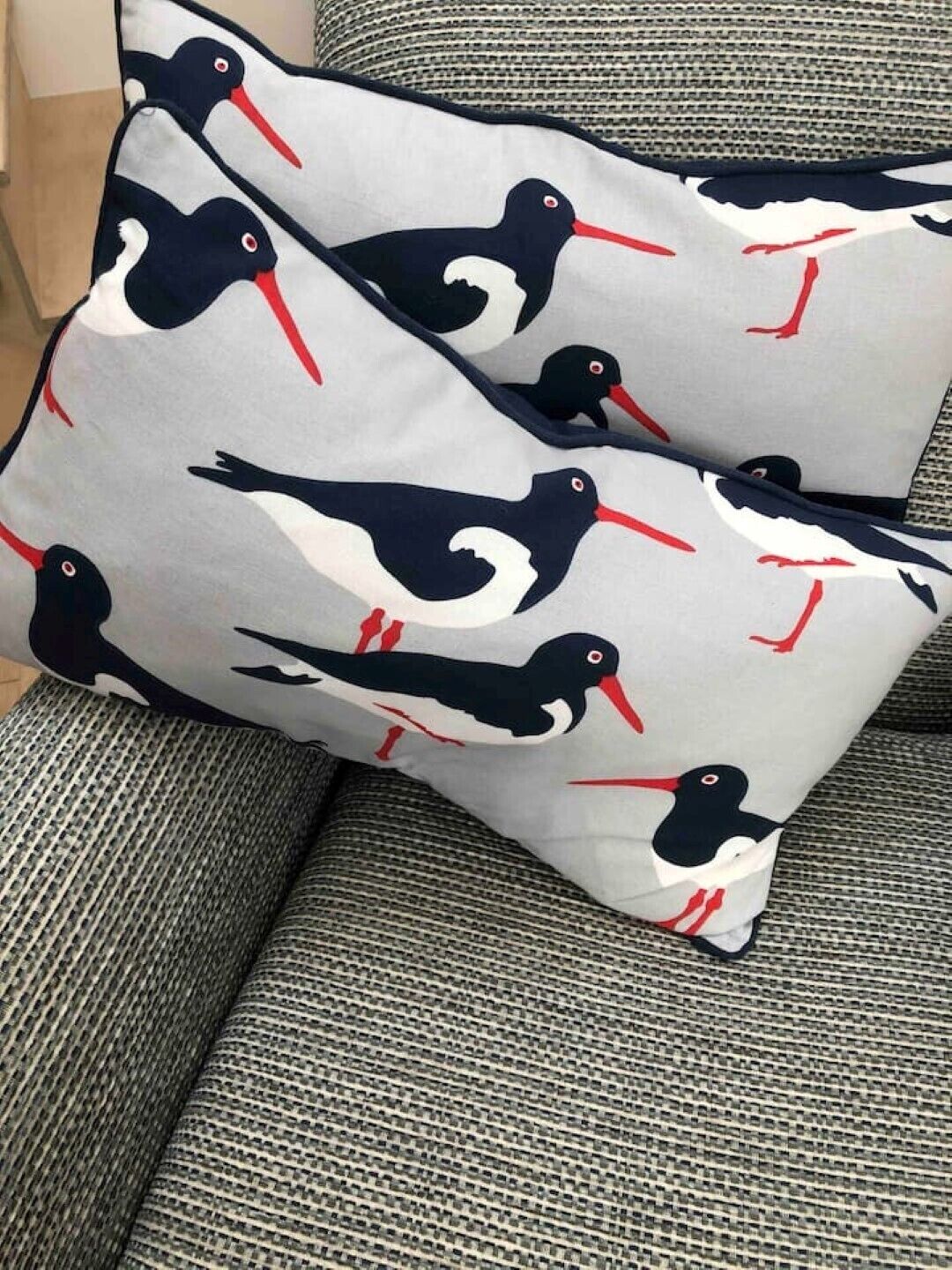 A pillow with a bird pattern on a textured fabric.