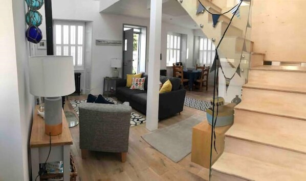 A spacious living area with a sofa, a coffee table, and a lamp. There is a staircase leading to an upper level.