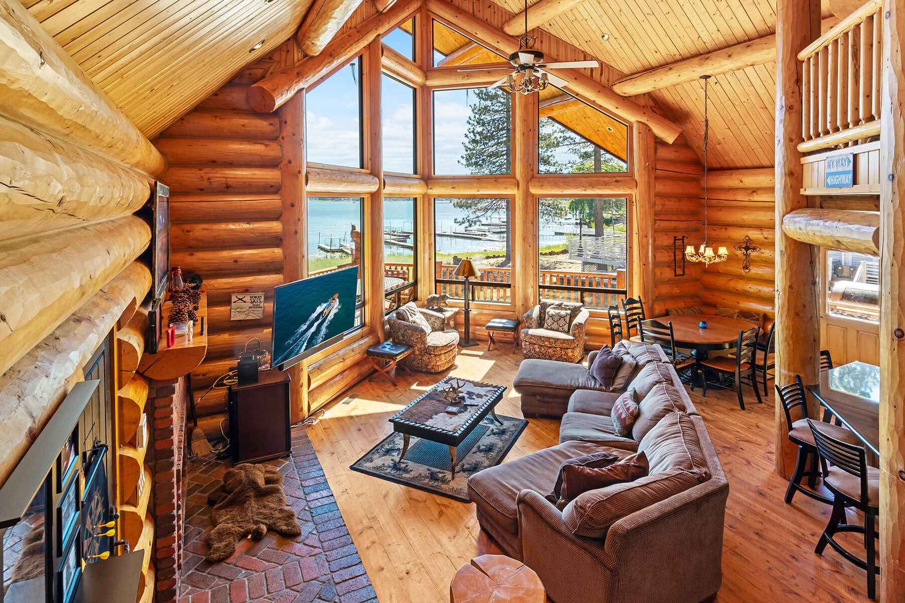 A log cabin interior with a large TV, comfortable seating, and a view of the outdoors.