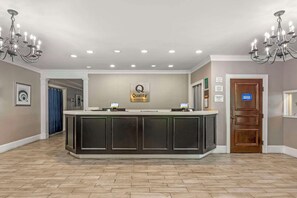 Un área de recepción con un mostrador central, una araña de cristal y un cartel que indica 'Quality by Choice Hotels'.