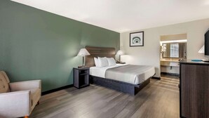 A hotel room with a bed, bedside tables, a chair, a desk, and a mirror. - Quality Inn & Suites Santee I-95 (Santee)