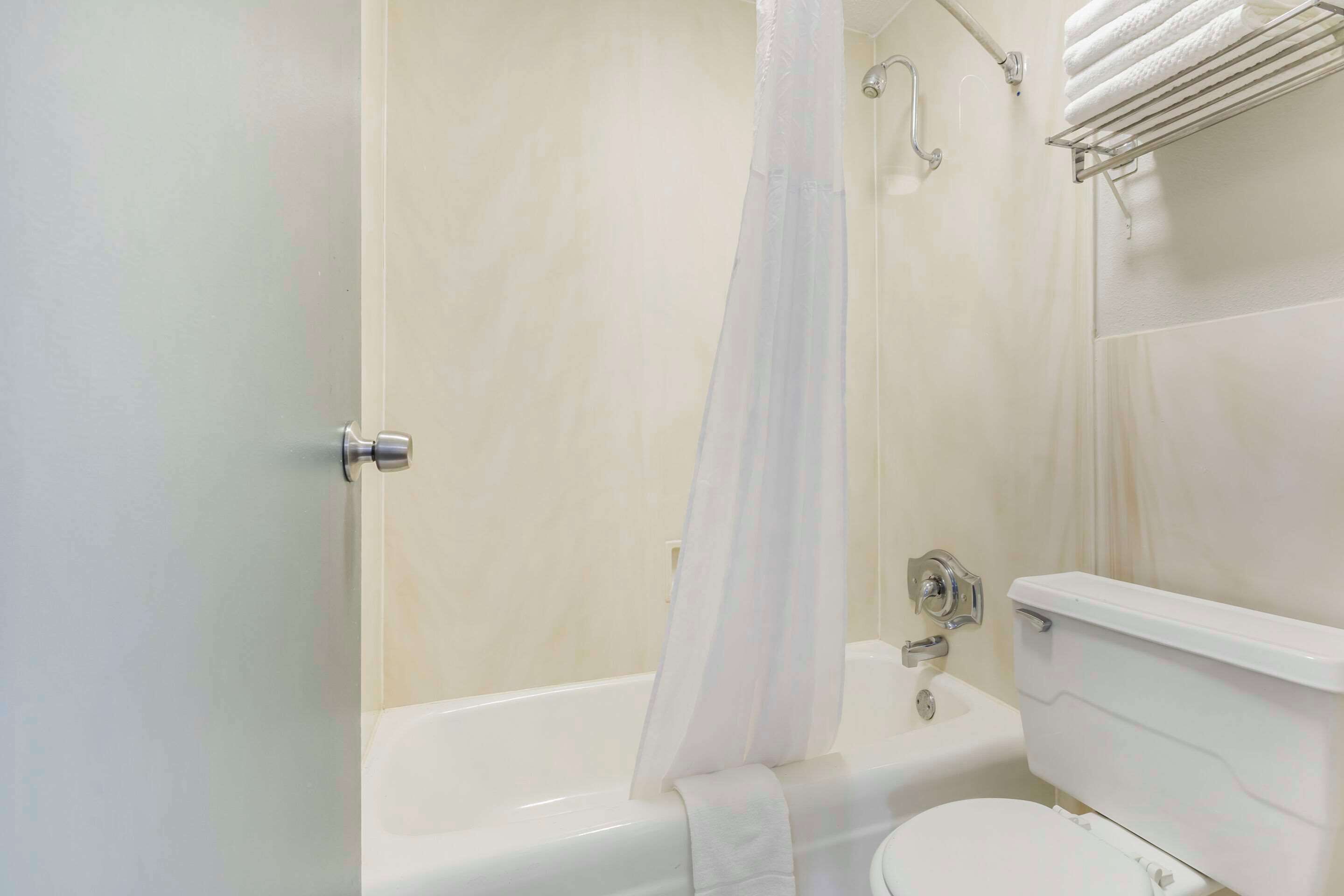 Un baño con bañera, inodoro y cortina de ducha.