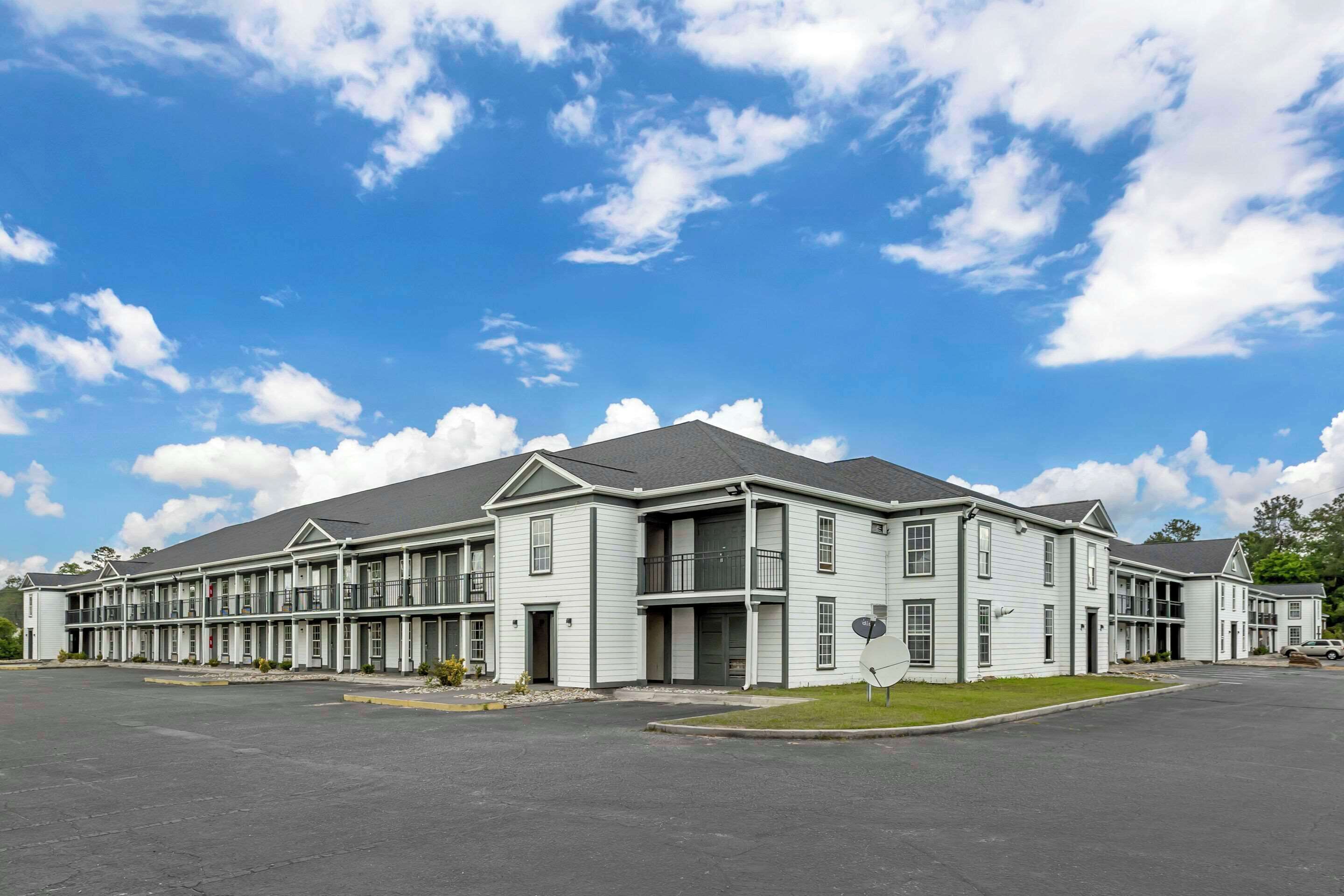 A multi-story motel with a central entrance, individual rooms on each floor, and a parking lot in front.