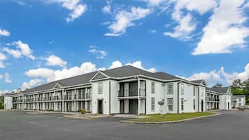 A multi-story motel with a central entrance, individual rooms on each floor, and a parking lot in front.