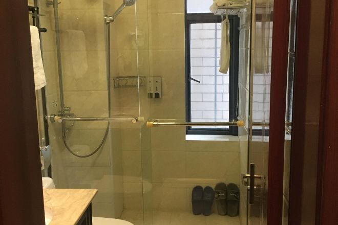 A glass-enclosed shower area with a glass door, a towel rack, and a pair of shoes on the floor.