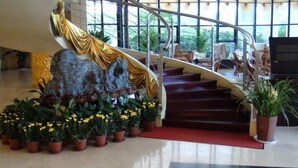 A grand staircase with a golden drape, surrounded by potted plants and a large rock sculpture. - Qingyuan Hotel University of Anhui (Hefei)