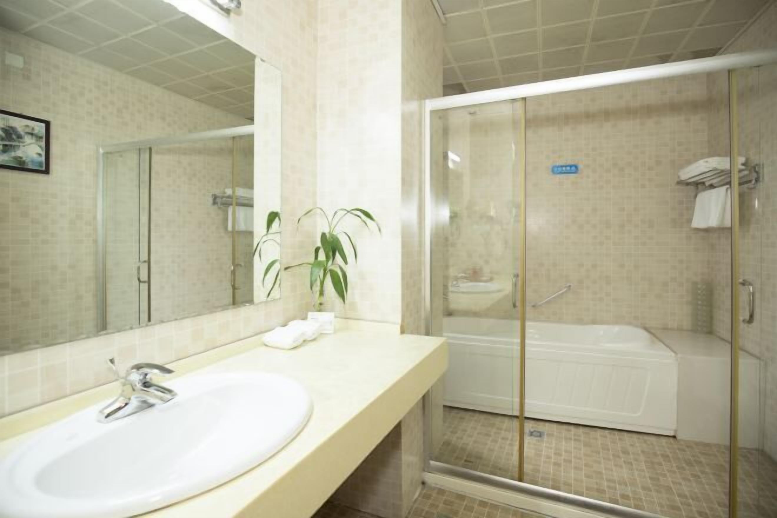 A bathroom with a sink, mirror, and shower area.