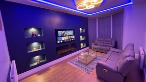 A modern living room with a flat-screen TV, built-in shelves, a fireplace, and a sectional sofa. - 1 Bed Flat - Sleeps 2 - Hot Tub - Parking - Wifi (Bradford)